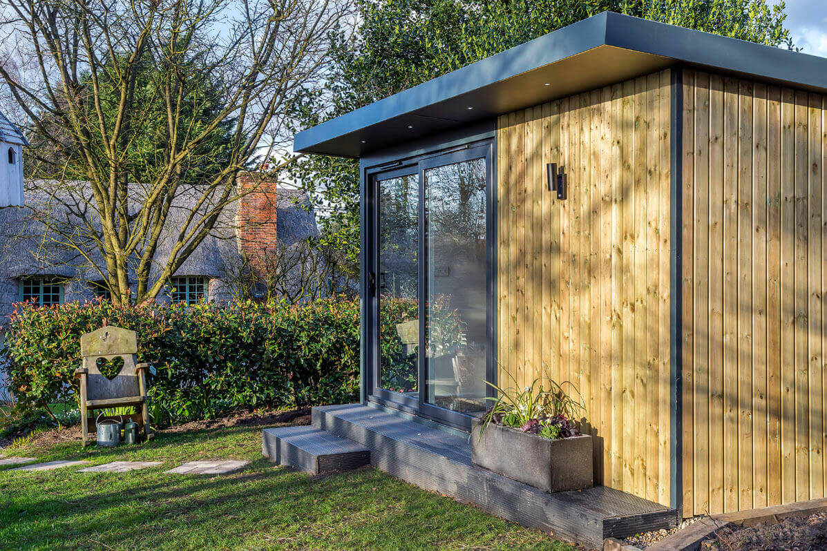 exterior view of a garden office that has exterior lights & a sliding door